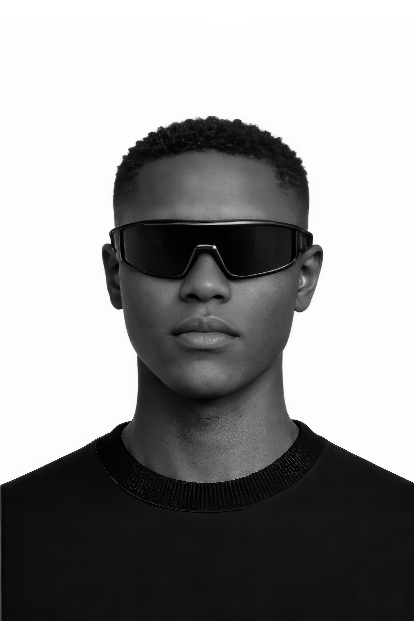 Person wearing black sunglasses and a black outfit on a white background