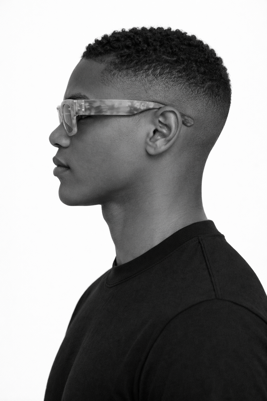 Side profile of a person wearing marbled sunglasses on a white background
