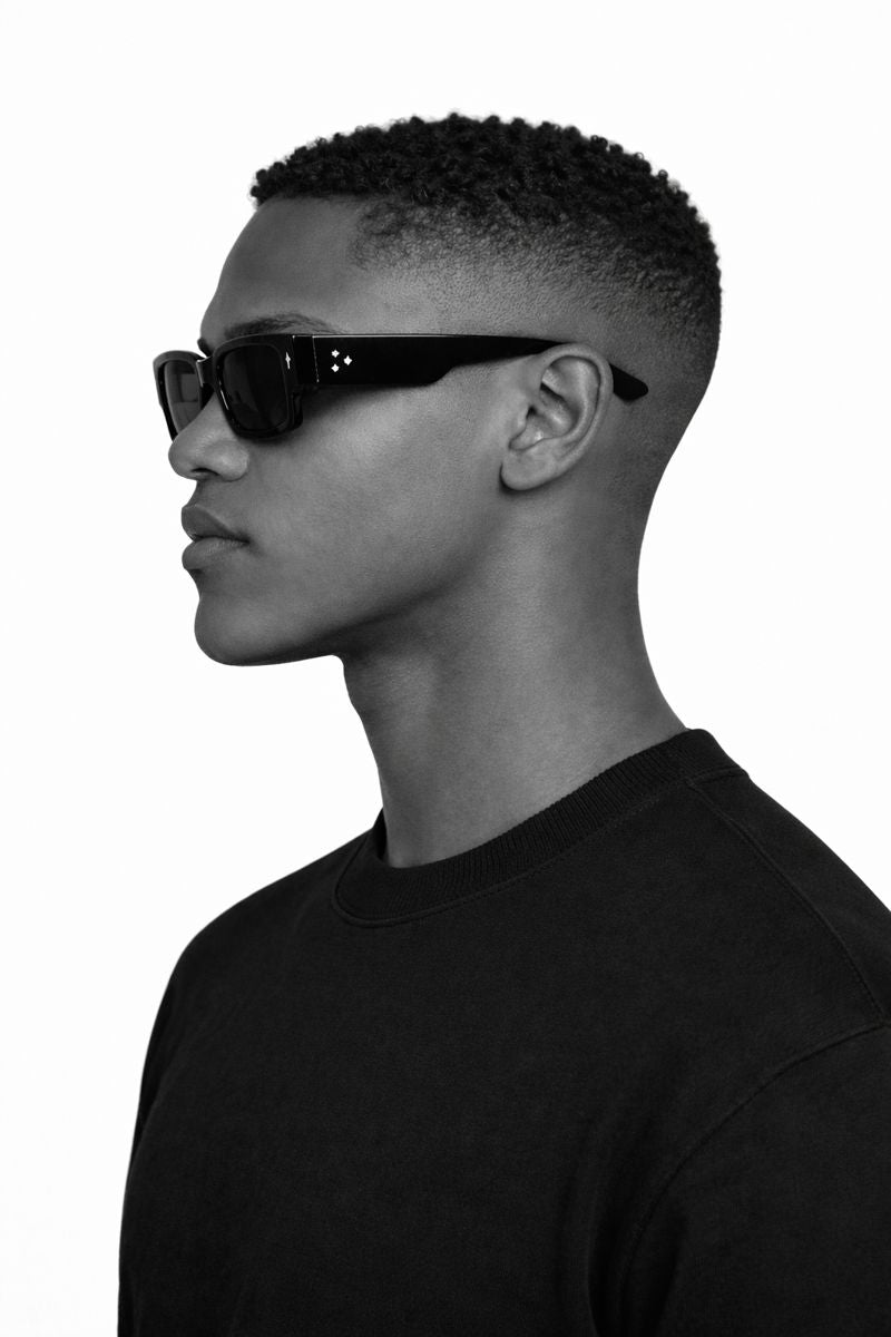 Black and white profile of a person wearing sunglasses and a black shirt.