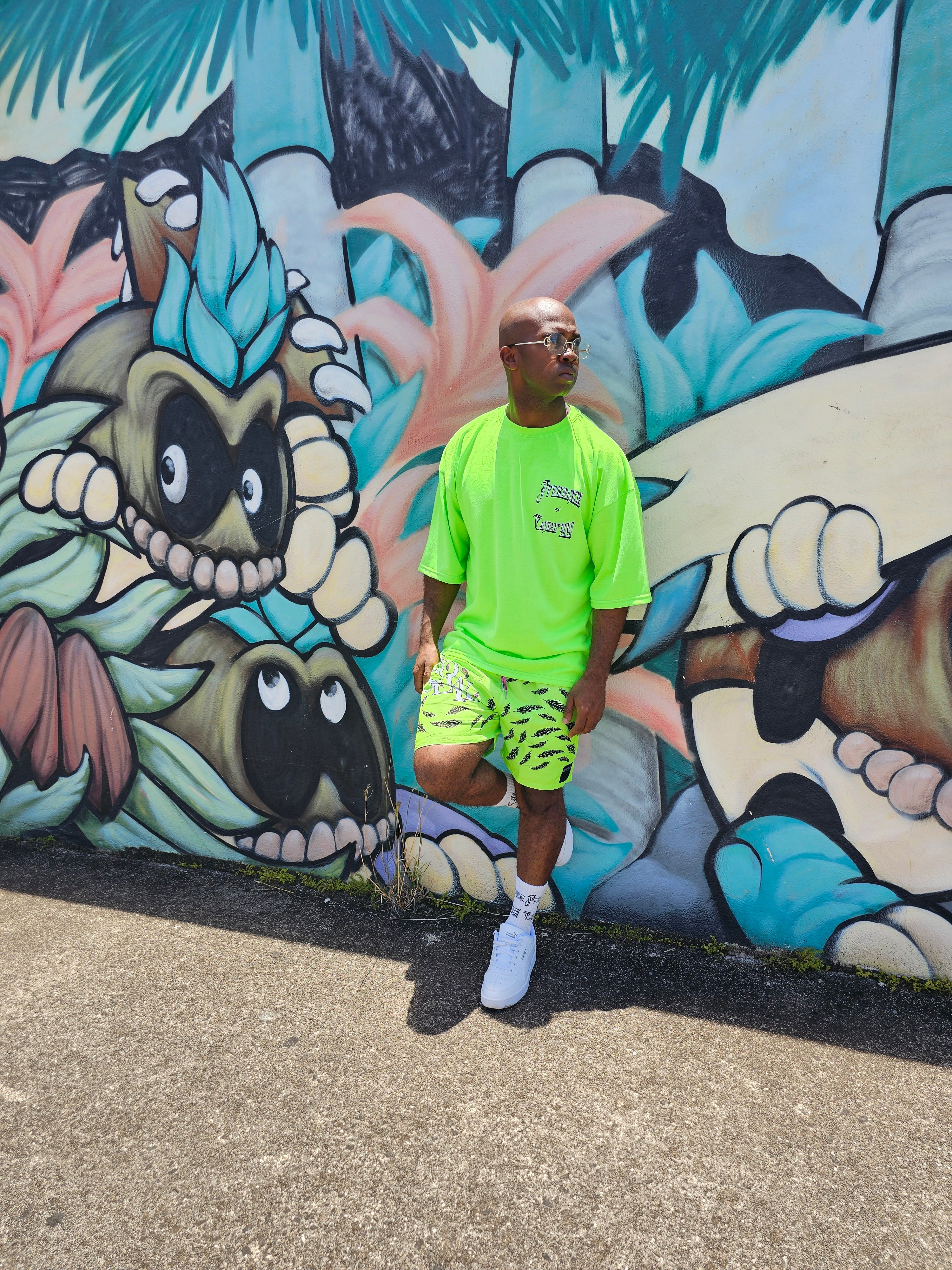 Person standing in front of a colorful mural on a wall.