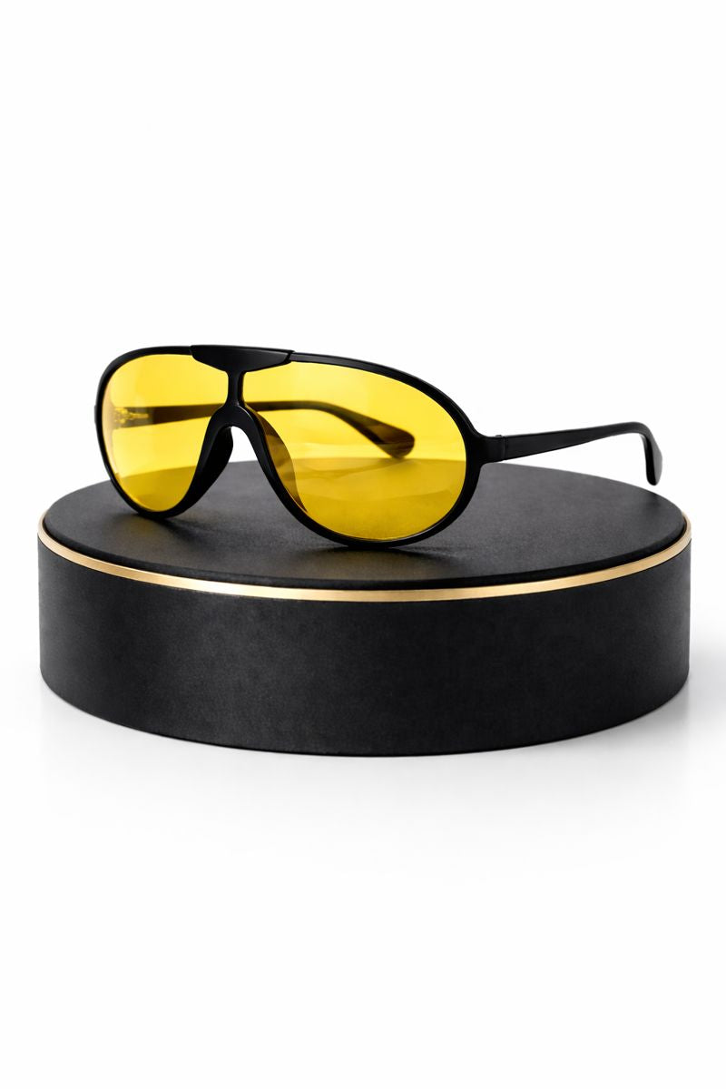 Yellow-tinted sunglasses on a black stand with a white background